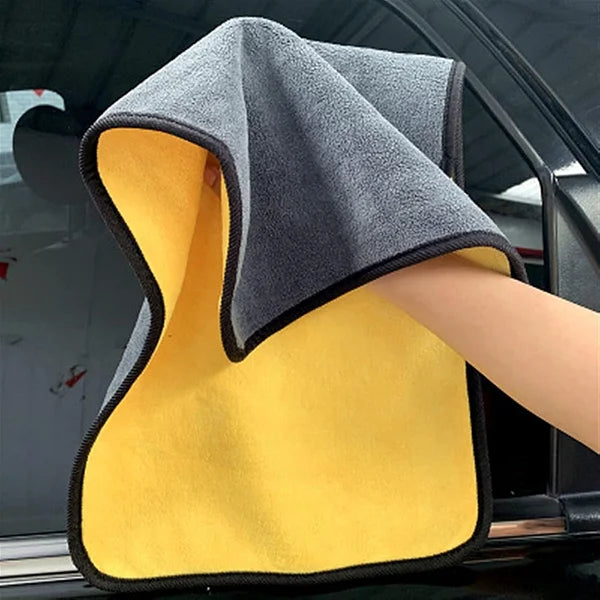 Gray and yellow microfiber towel held by a person inside a car.