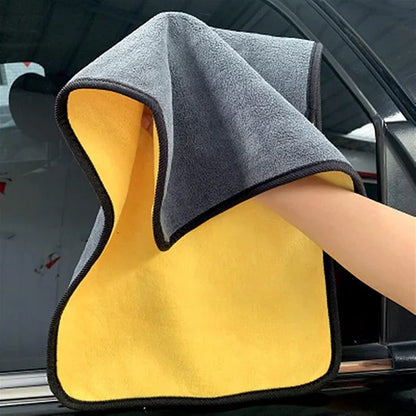 Gray and yellow microfiber towel held by a person inside a car.