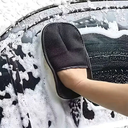 Person cleaning a car window with a black mitt covered in soap suds.