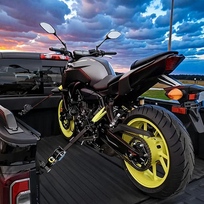 Motorcycle with yellow wheels on a car's open trunk against a sunset sky.