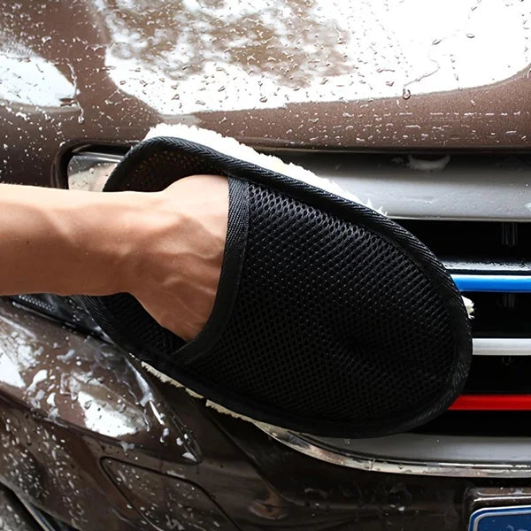 Person cleaning a car with a black microfiber mitt